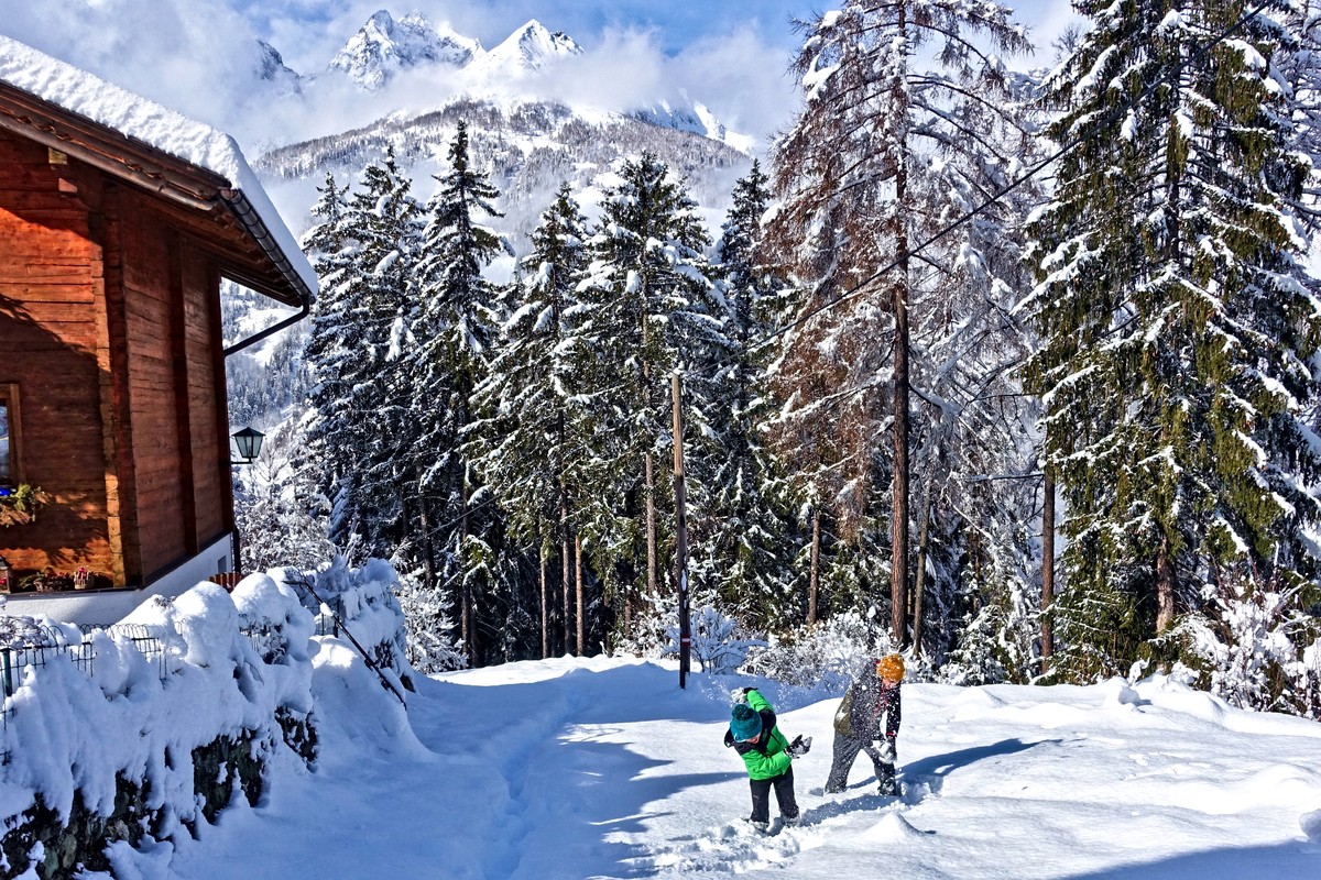 Sogno invernale per i vostri bambini - battaglia a palle di neve davanti allo chalet alpino